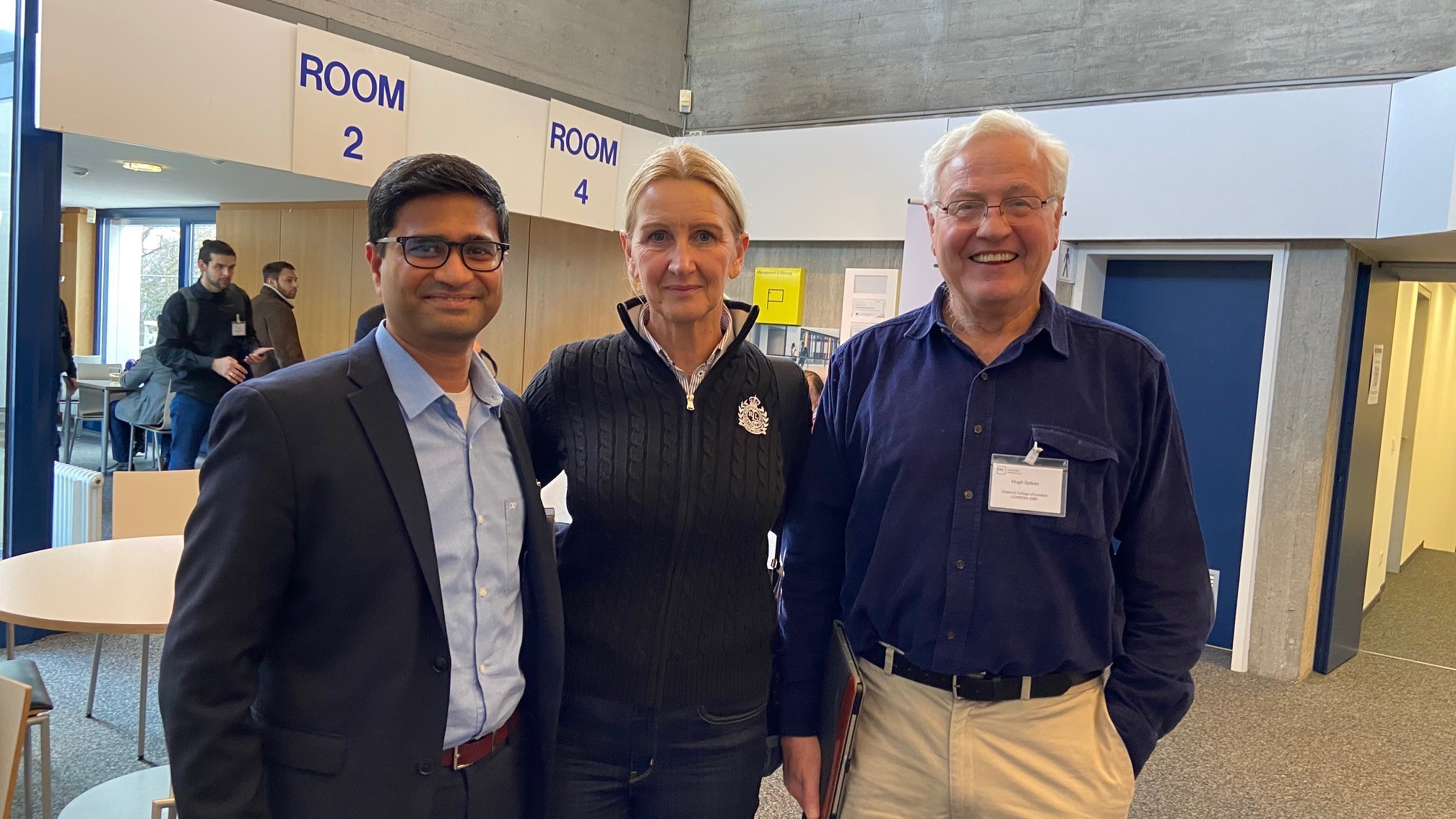 Two smiling men with glasses and a smiling woman